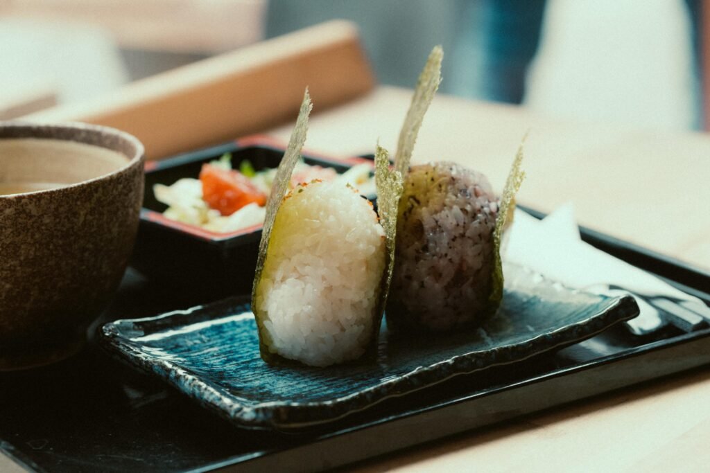 Close-up of Japanese onigiri sushi with traditional sides on a serving tray.